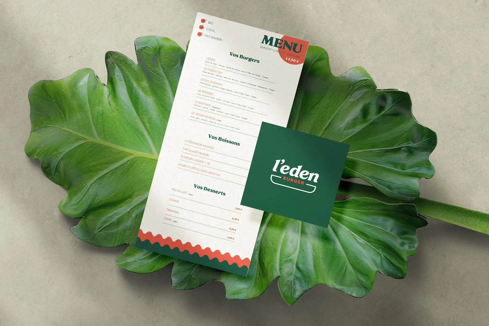 Menu L’Eden Burger et carte verte au logo crème posés sur une grande feuille.