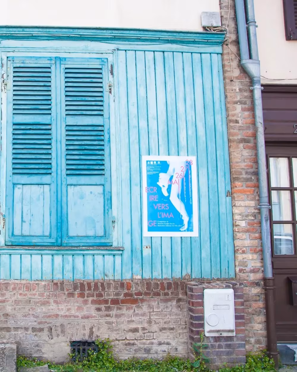 Affiche du colloque Écrire vers l'image posée sur une devanture turquoise